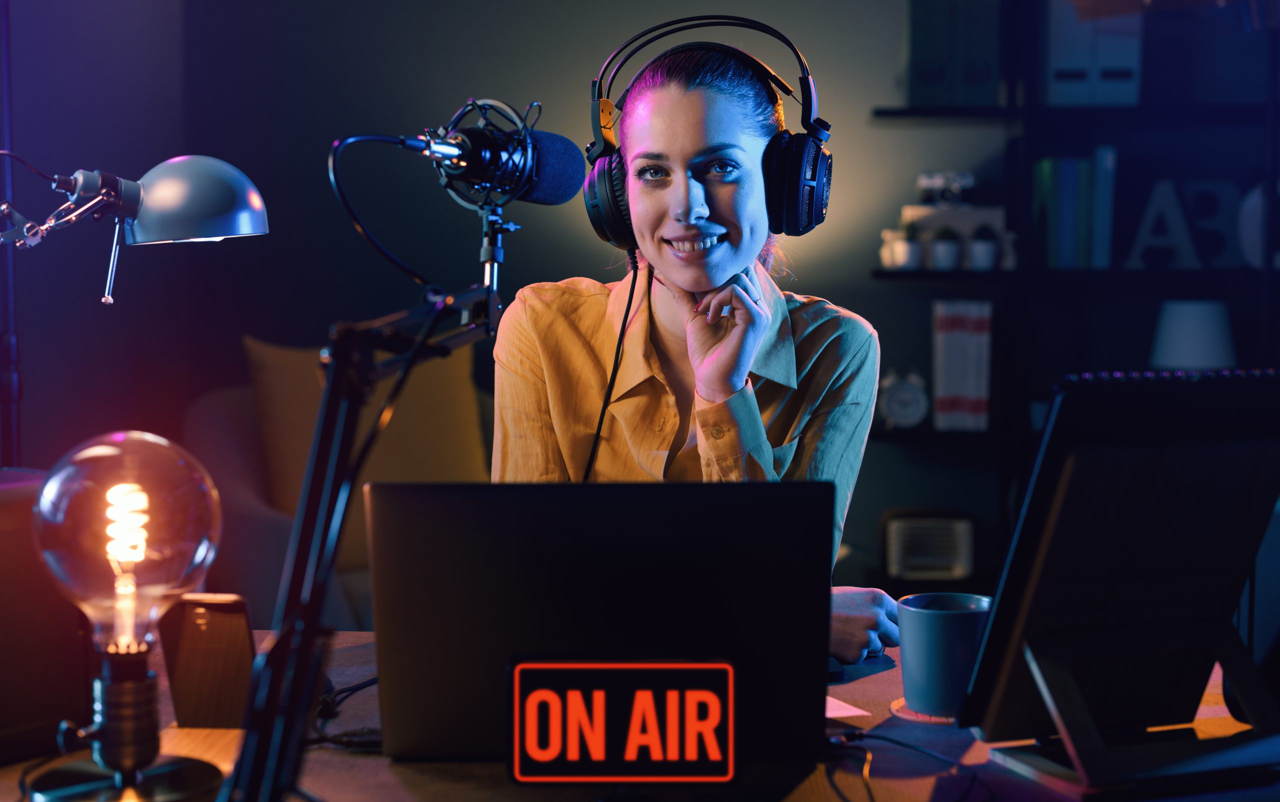 Young smiling radio host talking into a microphone and broadcasting at the radio station, entertainment and communication concept